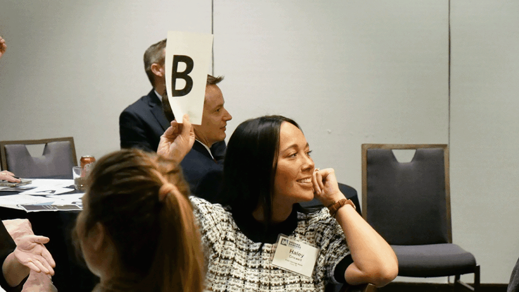a photo of a woman holding up a paper to answer a question during a trivia challenge