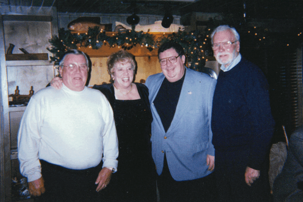 Three men and a woman are seen wearing business casual clothing at a Christmas party