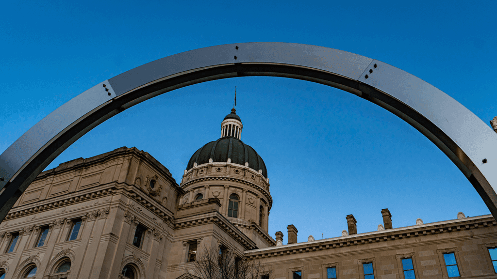 a photo of the Indiana Statehouse including an art piece on the Statehouse grounds