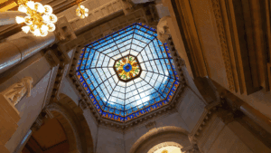 a photo looking up at the stained glass of a dome on the Indiana Statehouse from inside the building