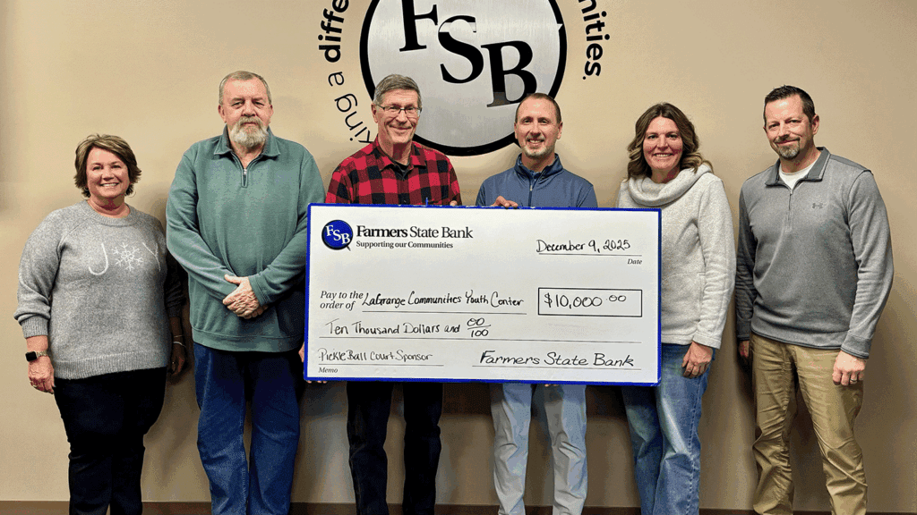 a photo showing six people in business casual clothing holding a ceremonial check marking a $10,000 donation