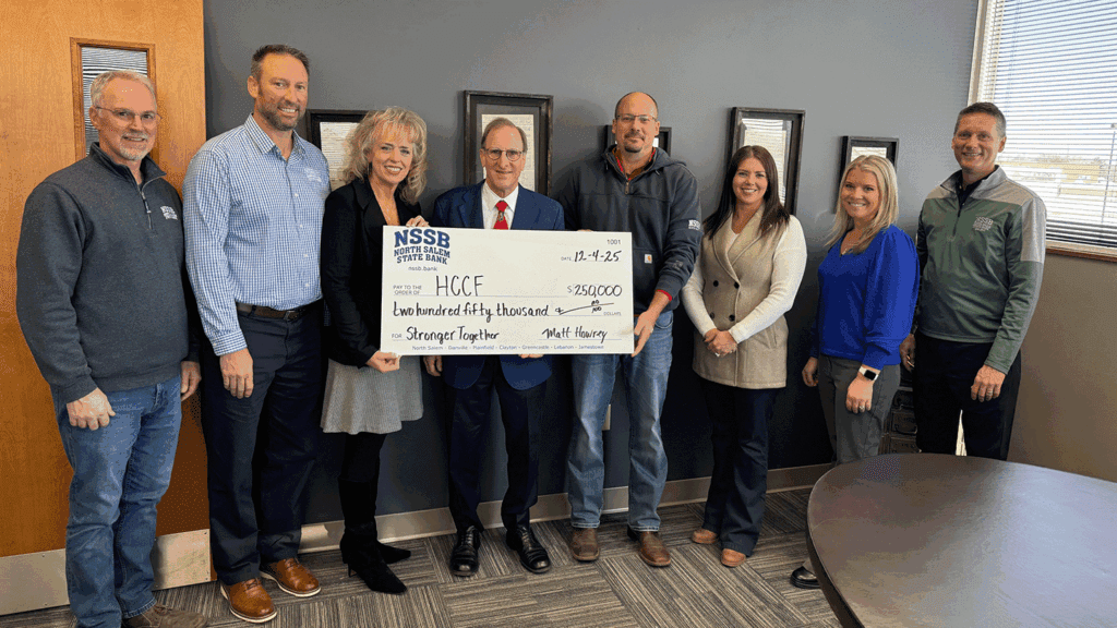 a photo showing eight people holding a ceremonial check marking a $250,000 donation
