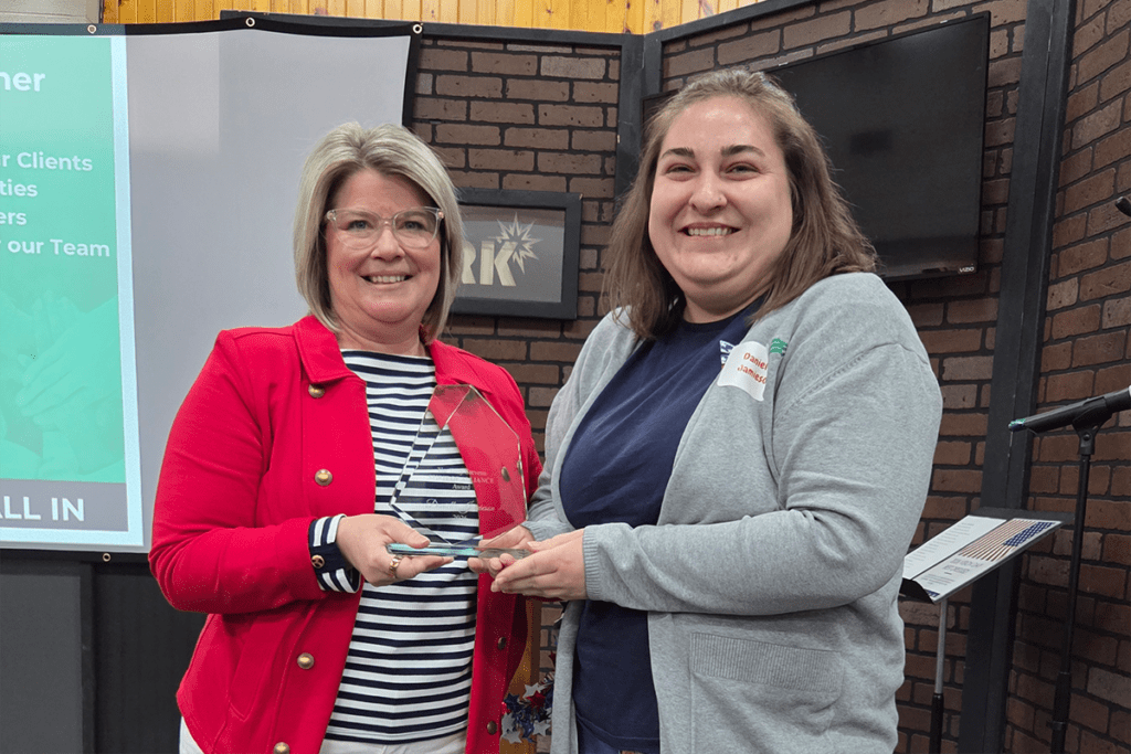a photo showing two women in professional clothing with one handing the other an award