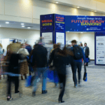 a crowd of people walking into a conference center hall