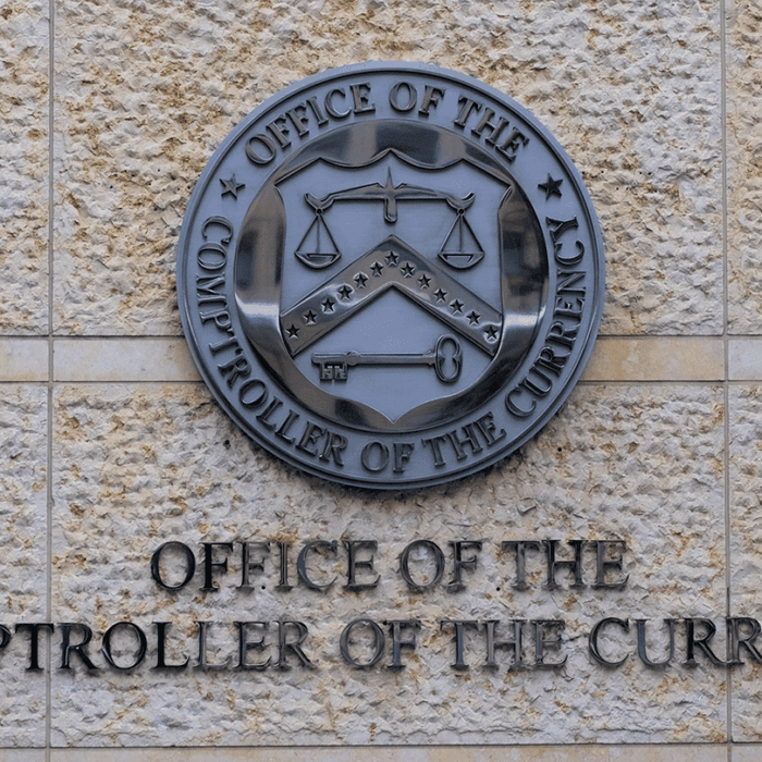 a photo of the office's seal on an exterior wall at the Office of the Comptroller of the Currency in Washington, D.C.