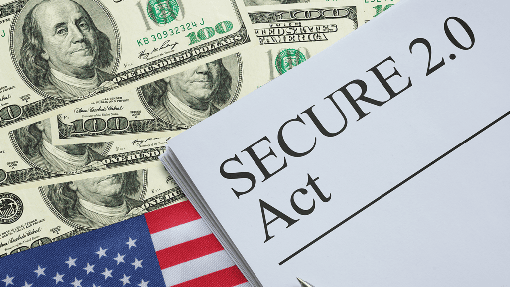 Document labeled 'SECURE 2.0 Act' resting on a stack of US $100 bills and a small American flag, suggesting financial legislation context.
