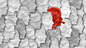 Row of gray paper-cut silhouette profiles facing left; one red figure wearing a headset stands out among them.