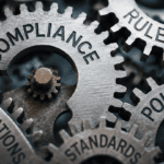 Interlocking metal gears labeled Compliance, Rules, Policies, Regulations, and Standards.