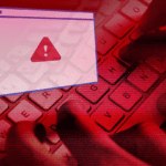 Red-tinted image of a computer keyboard with a pop-up warning icon signaling a security alert.