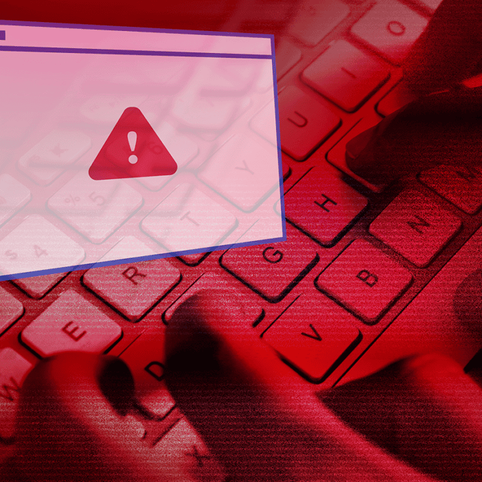 Red-tinted image of a computer keyboard with a pop-up warning icon signaling a security alert.